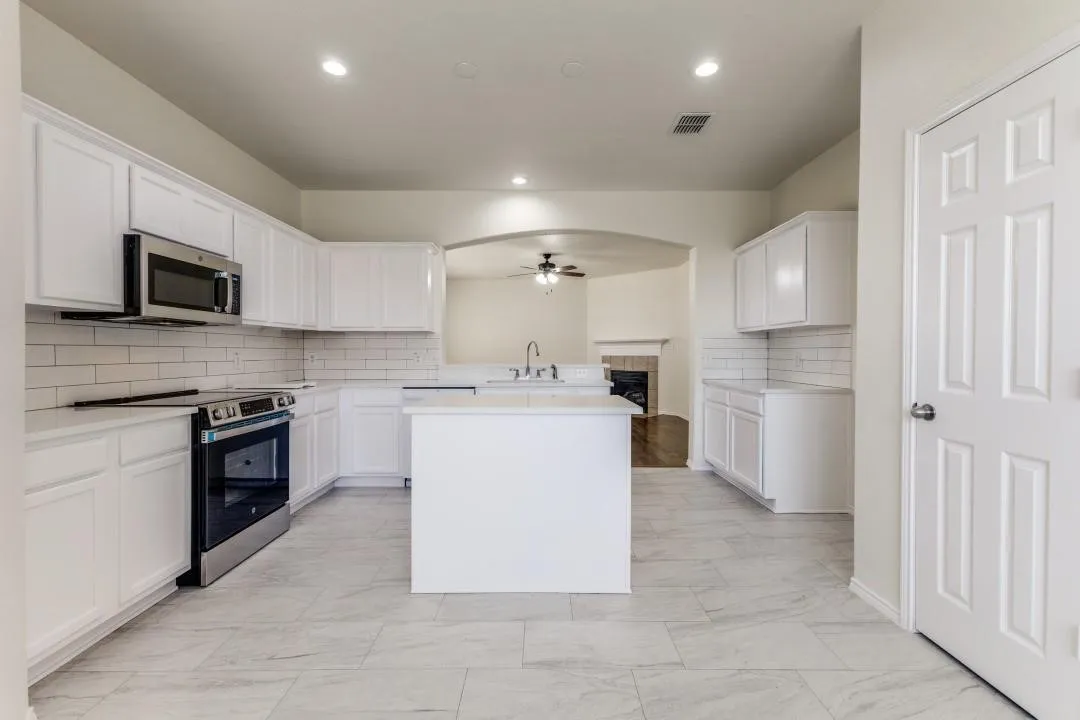 Kitchen featuring white cabinetry, subway tile backsplash, stainless steel appliances, a central island, and tile flooring