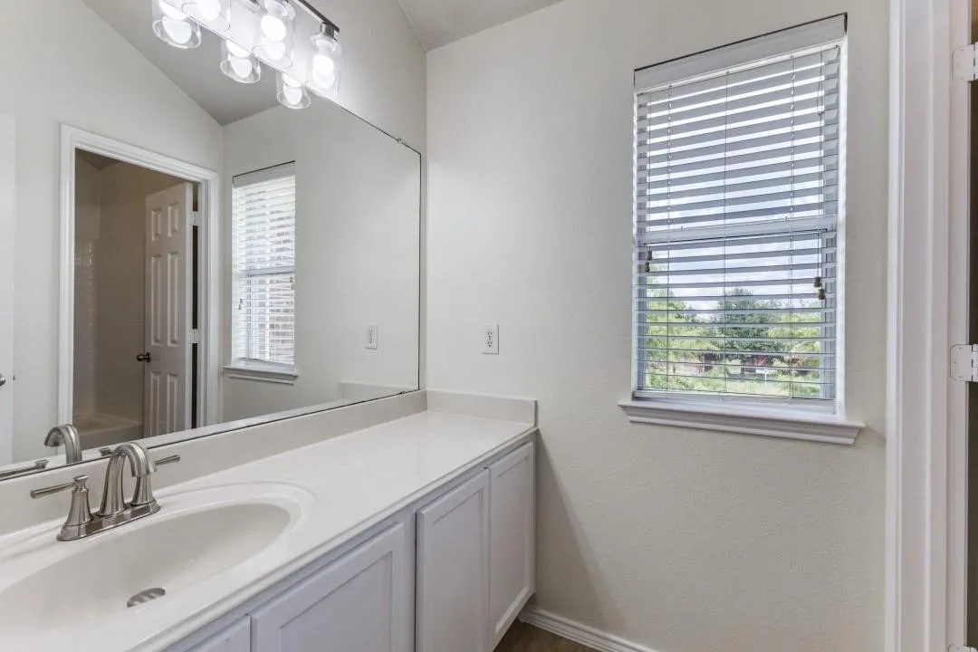 Extended vanity with white cabinetry, integrated sink, and brushed nickel faucet