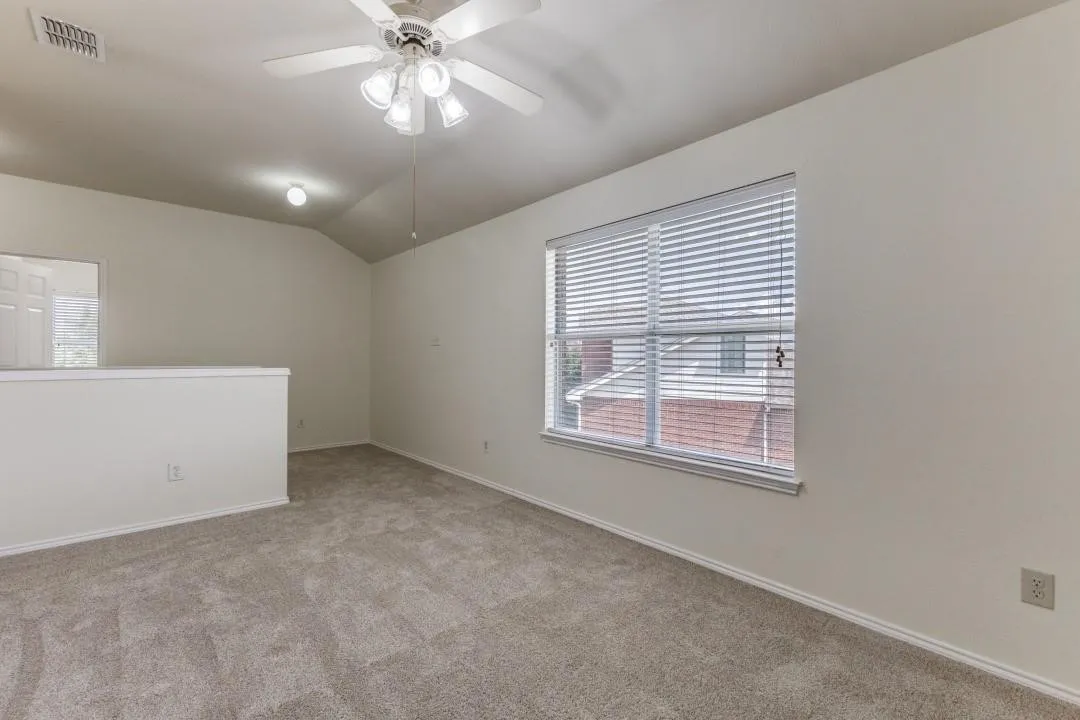Vaulted ceiling, ceiling fan with light fixture, carpeted flooring, window with blinds, and white wall finishes