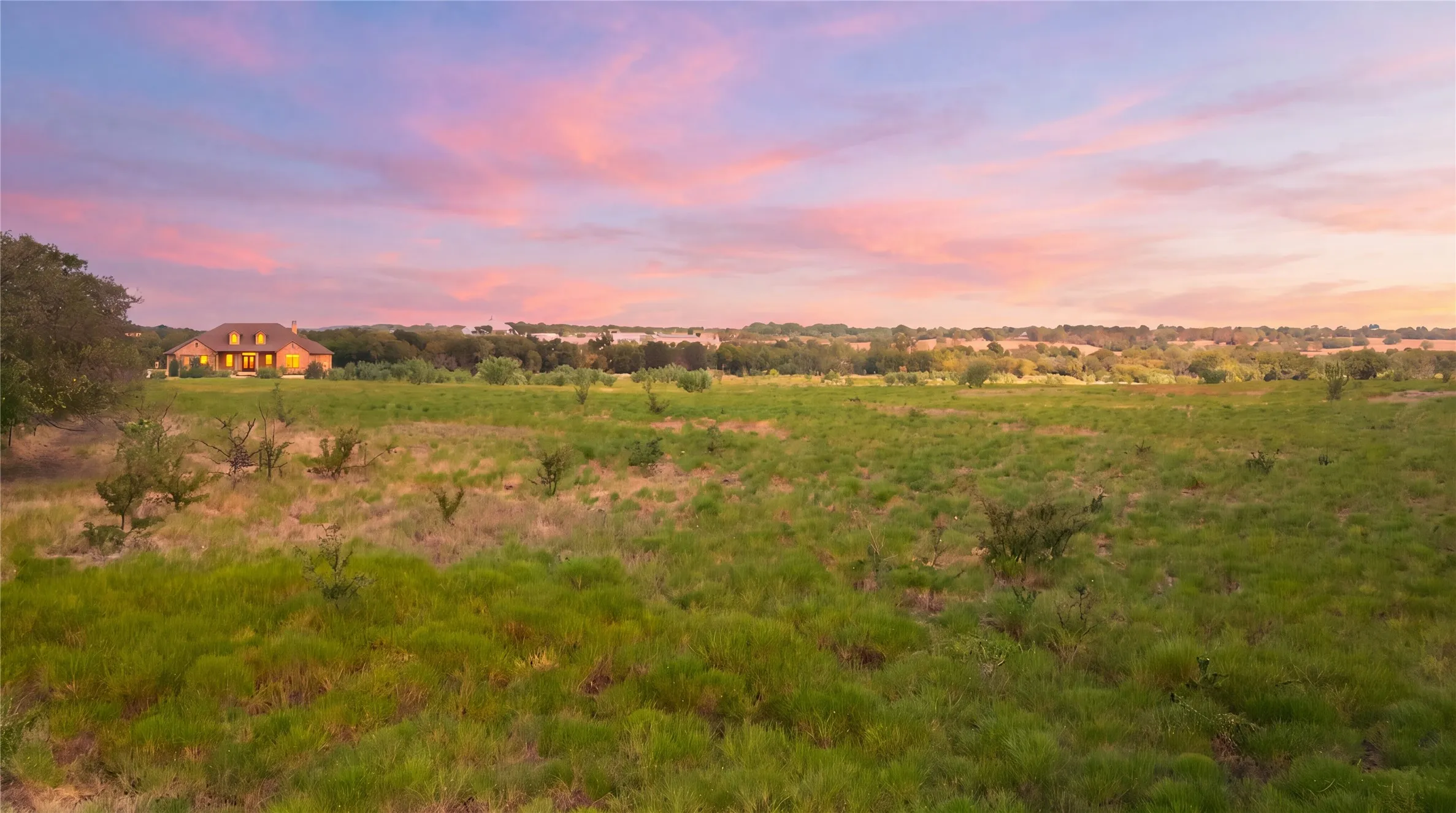 Expansive grassy landscape with distant residential structures