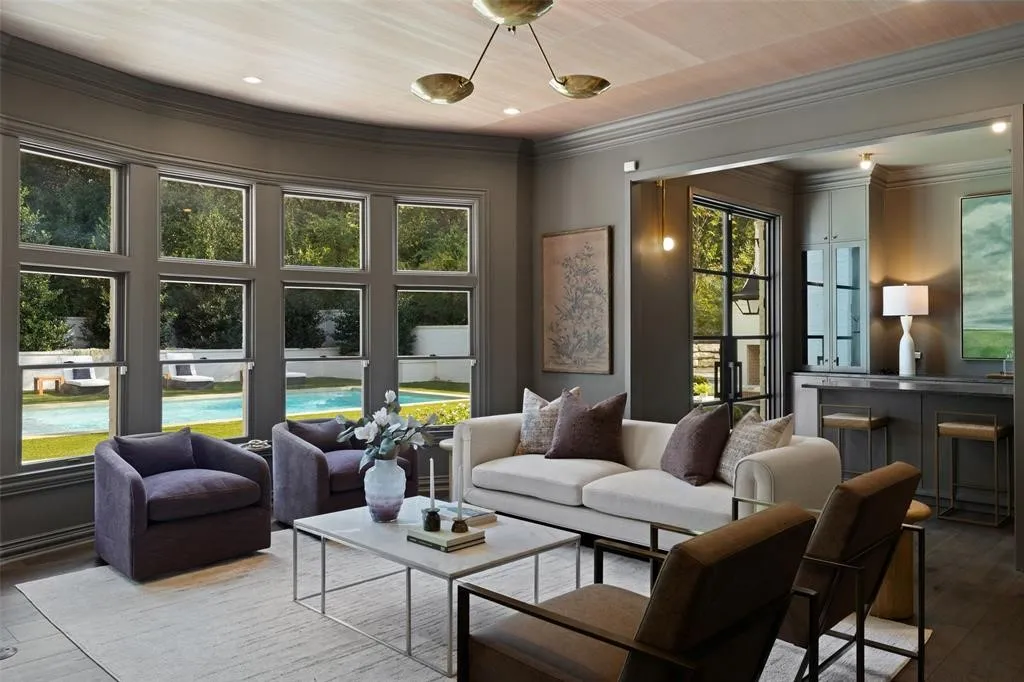 Curved wall of windows, hardwood flooring, built-in wet bar with cabinetry, recessed lighting, and a modern chandelier