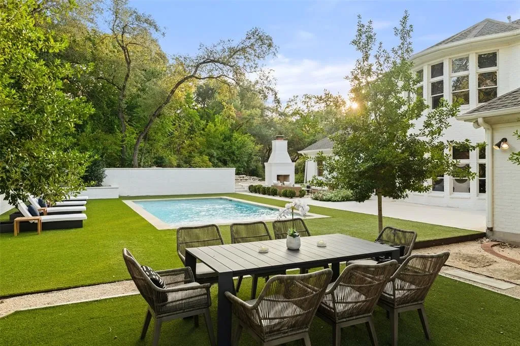 Expansive backyard with a swimming pool, artificial turf, and a built-in outdoor fireplace