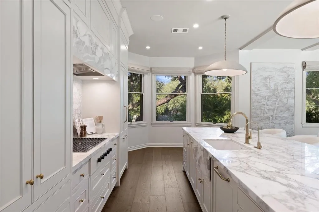 White cabinetry with gold-finish hardware, built-in gas range, wood-finish flooring, white kitchen island with undermount sink, and recessed lighting