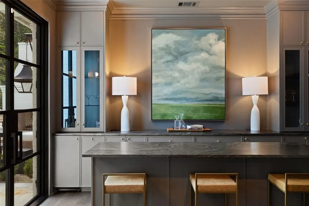 Built-in cabinetry with glass-front display, undermount lighting, and stone countertops