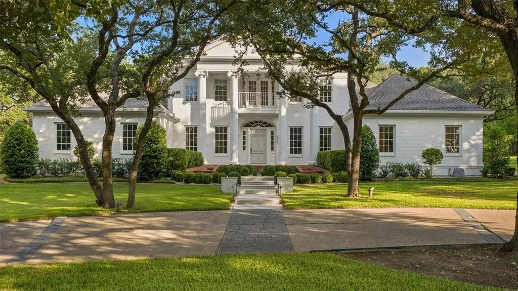 White brick facade with a grand portico entry featuring columns and an upper-level balcony