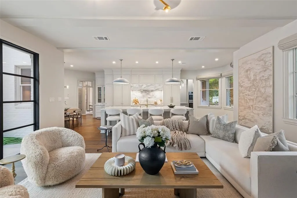 Open-concept living area with wood-finish flooring, a kitchen island, white cabinetry, and recessed lighting
