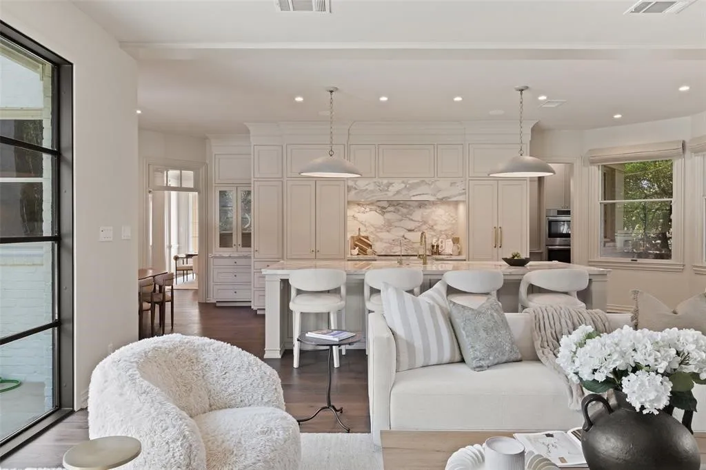 Gourmet kitchen with custom cabinetry, large island with seating, integrated appliances, and a marble backsplash