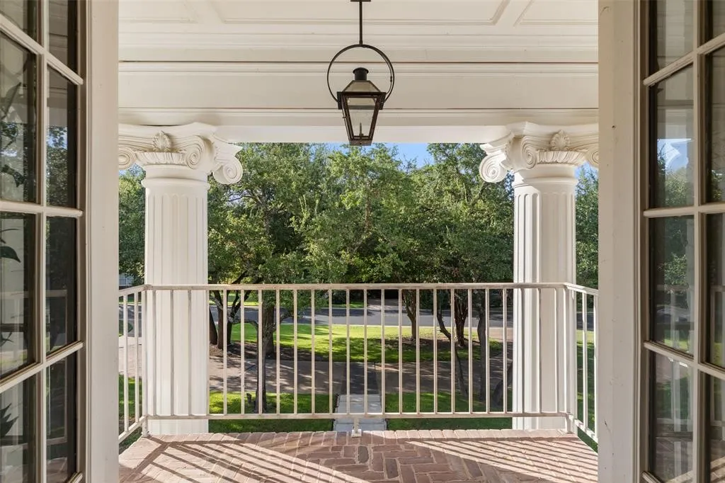 Portico with brick flooring, fluted columns featuring ornate capitals, and a white balustrade