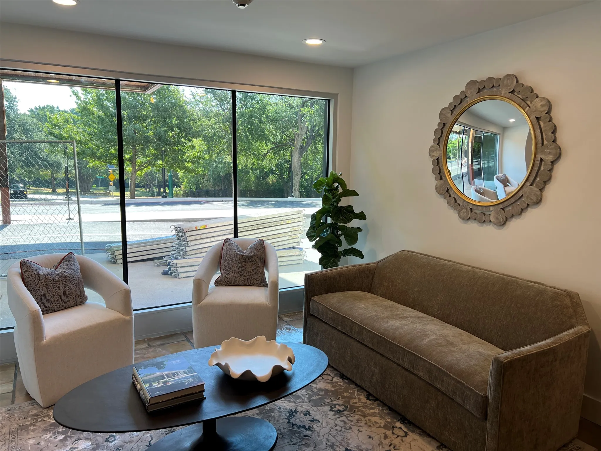 Recessed lighting illuminates the space, featuring a large window with exterior views and a decorative wall mirror