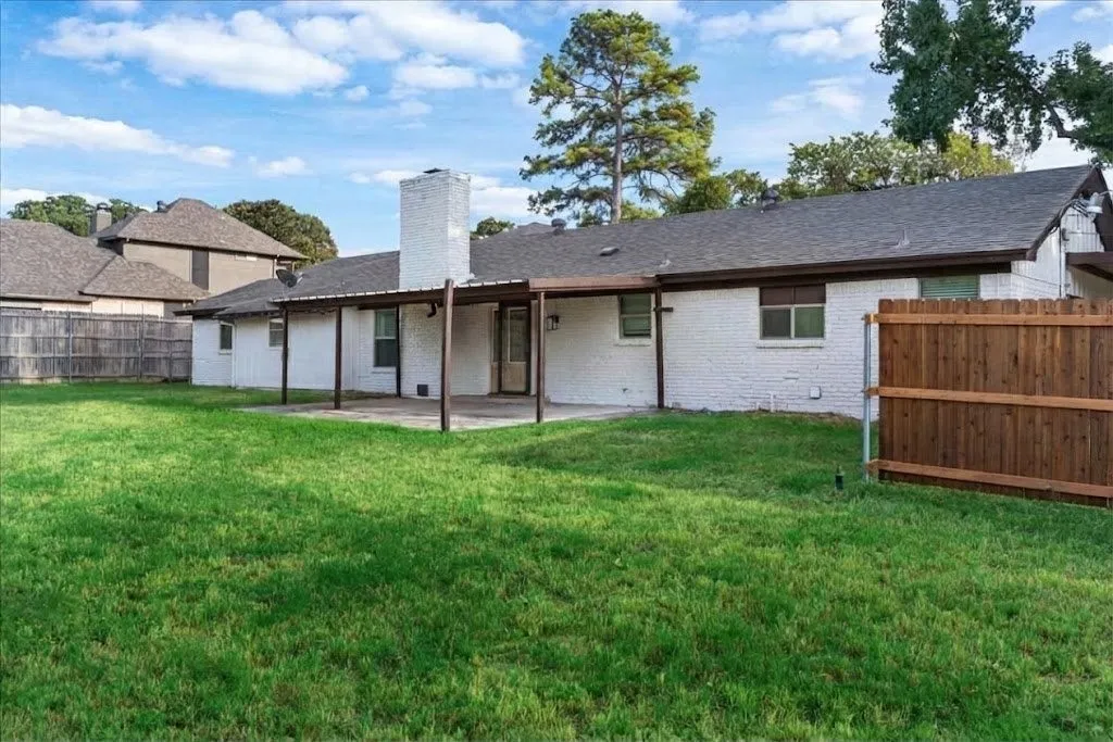 Expansive backyard featuring a manicured lawn, a covered patio, and a privacy fence