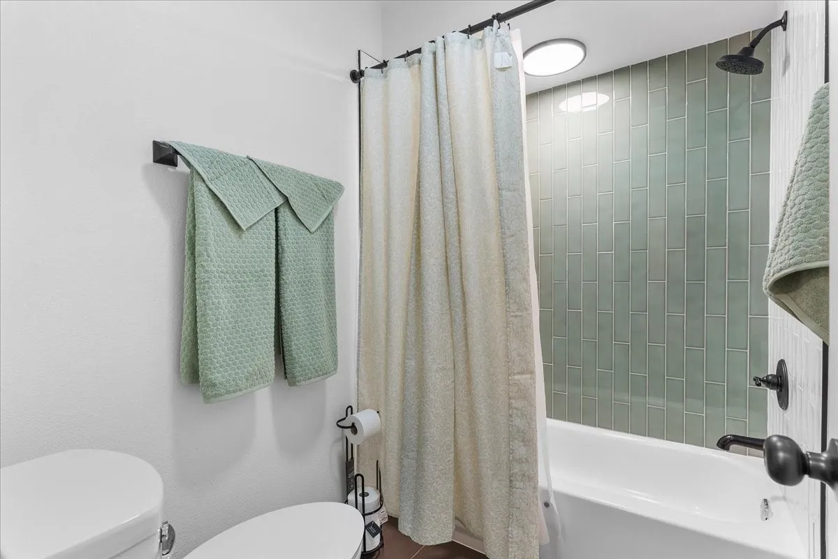 Built-in bathtub with subway tile surround, matte black shower head, and matte black fixtures