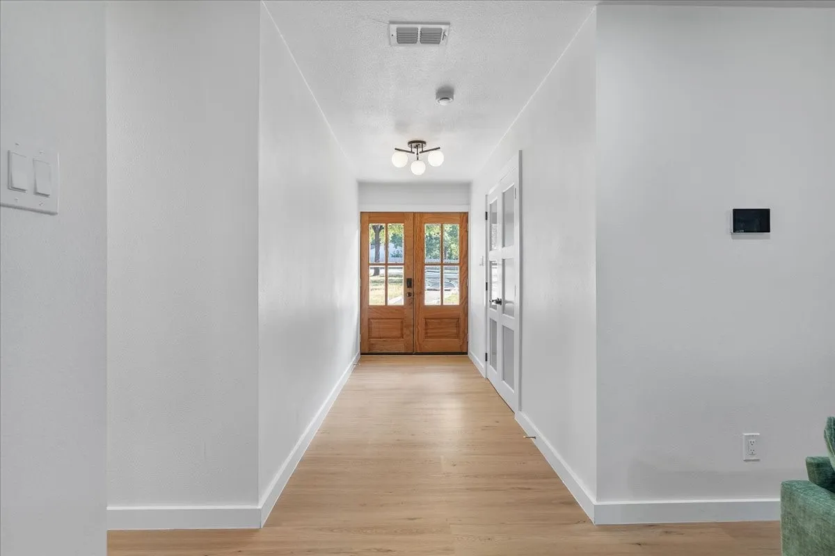 Light wood-finish flooring, white walls, and recessed lighting