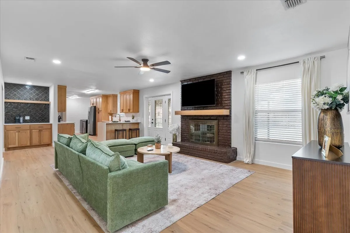 Living room featuring wood-finish flooring, a brick fireplace with a wood mantel, and recessed lighting