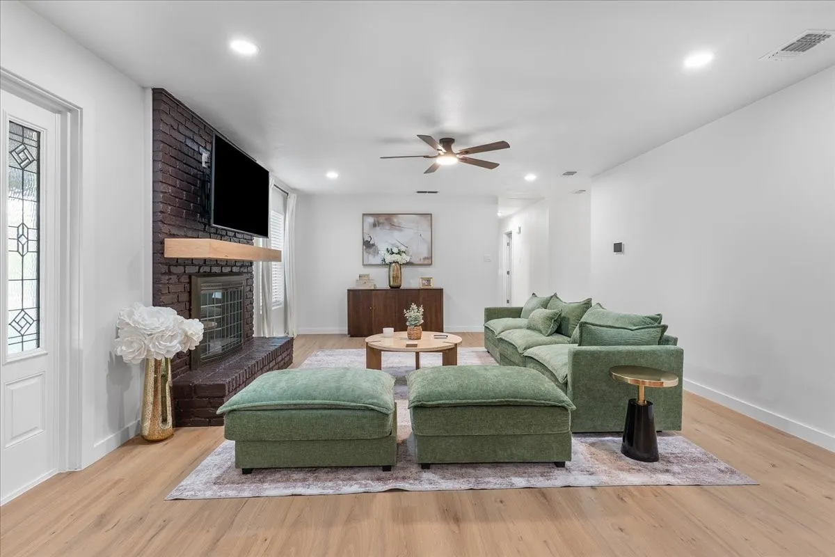 Wood-finish flooring, recessed lighting, and a dark brick fireplace with a wood mantel