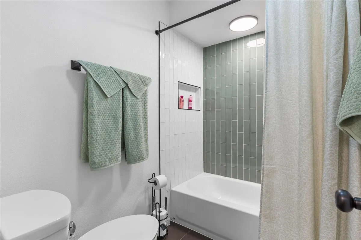 Bathtub with full-height subway tile surround, recessed niche, and integrated ceiling lighting