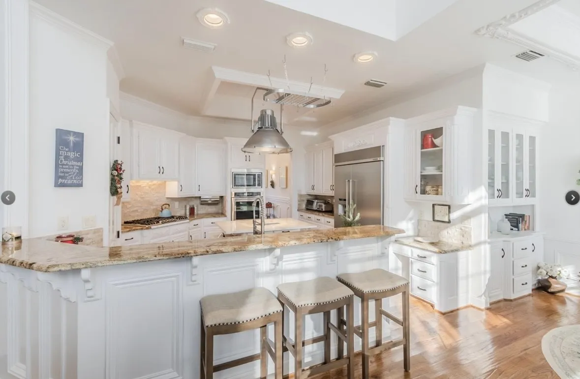 Kitchen featuring white cabinetry, built in appliances, kitchen peninsula, light stone counters, and light hardwood / wood-style floors