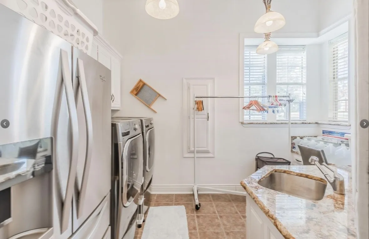 Laundry room with washing machine and clothes dryer, cabinets, sink, and light tile patterned floors