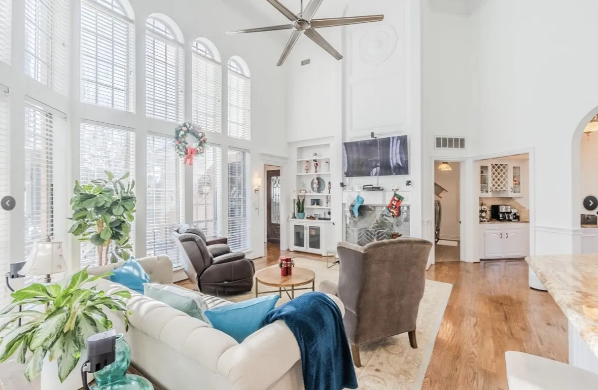 Living room with light wood-type flooring, a healthy amount of sunlight, ceiling fan, and a towering ceiling