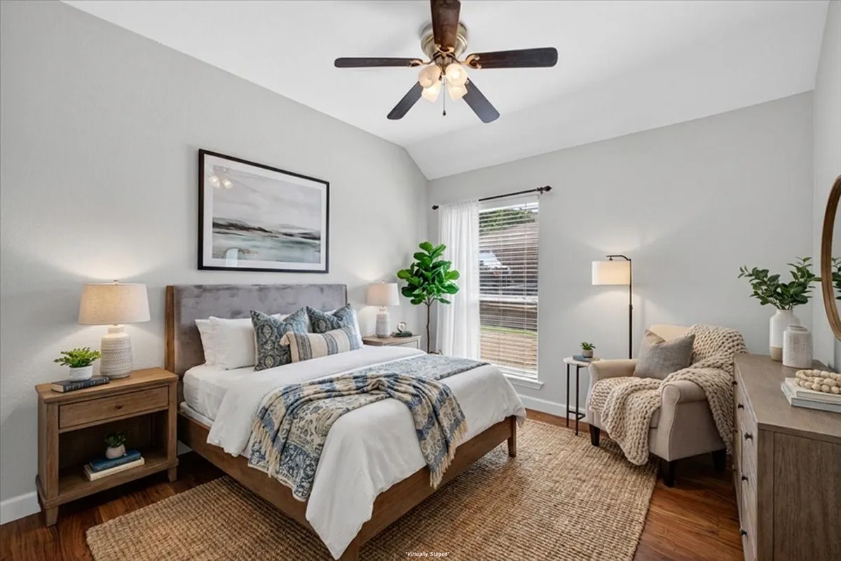 Vaulted ceiling with a ceiling fan, wood-finish flooring, window with blinds and sheer curtains, and light-toned walls