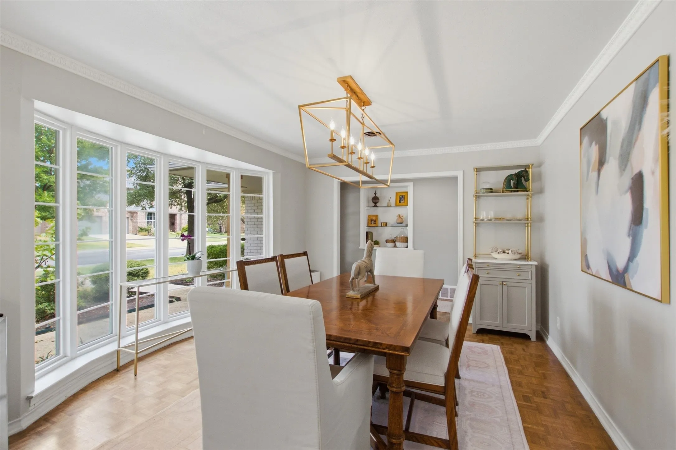Bay window with multiple panes, crown molding, wood-finish flooring, built-in shelving, and a decorative chandelier