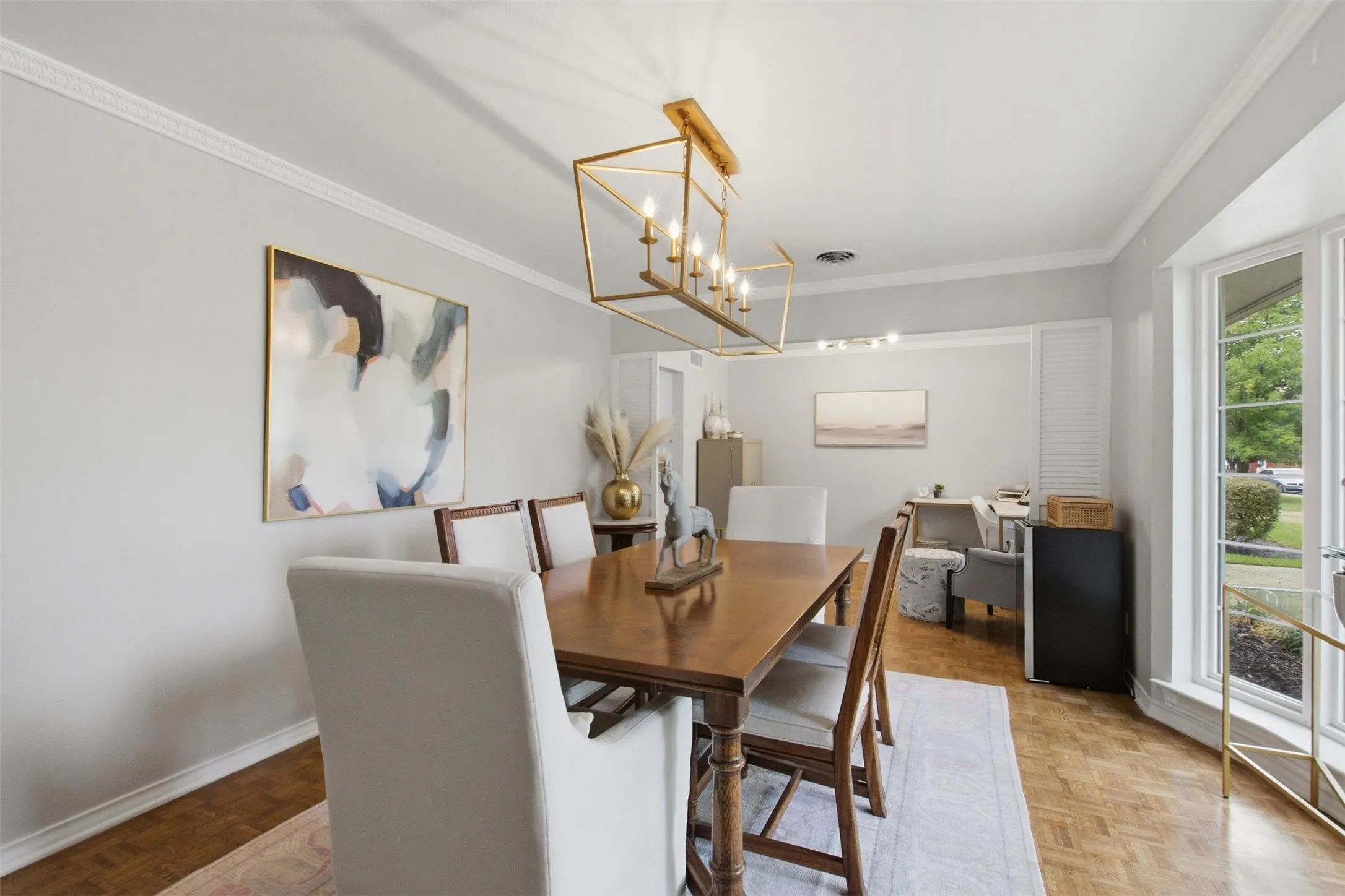 Formal dining area featuring crown molding, a multi-pane window, wood-finish flooring, and a gold-tone linear chandelier