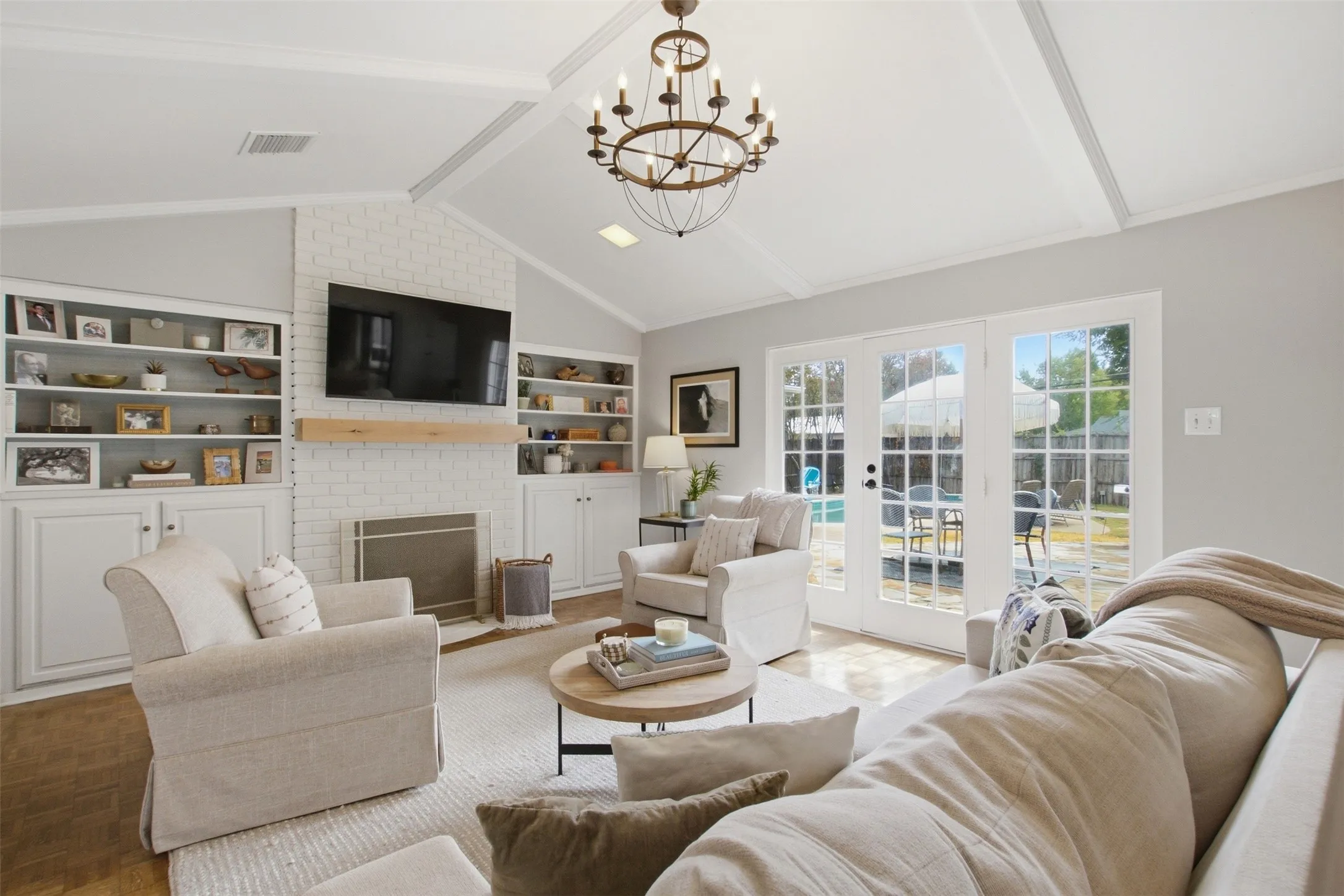 Vaulted ceiling with exposed beams and a decorative chandelier