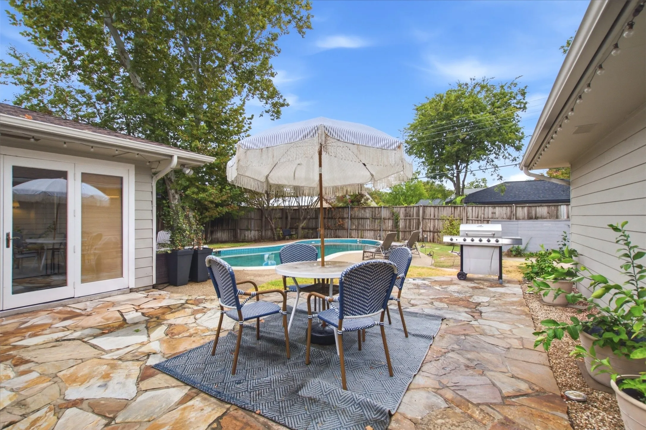 Flagstone patio with a swimming pool, wood privacy fence, and white siding