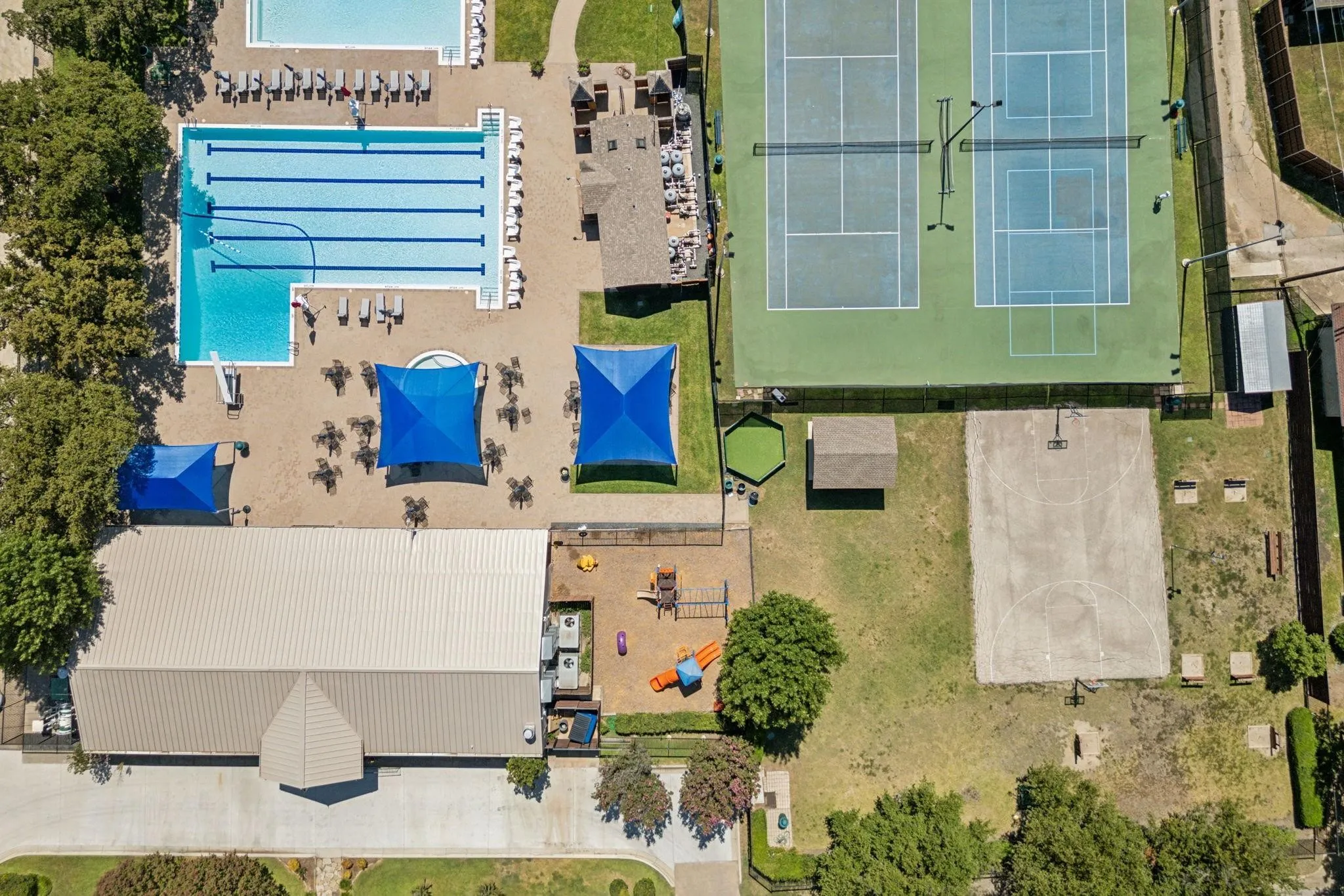 Community recreation area featuring a large swimming pool, two tennis courts, a basketball court, and a playground