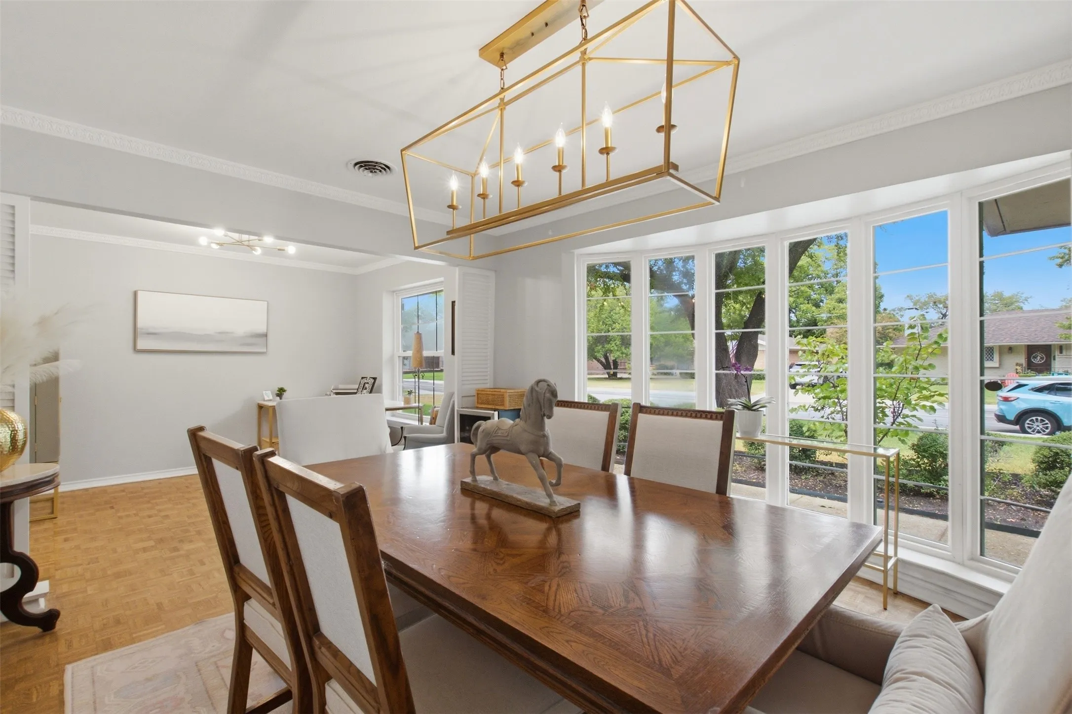 Bay window with multiple panes, crown molding, wood-finish flooring, and a gold-tone geometric chandelier