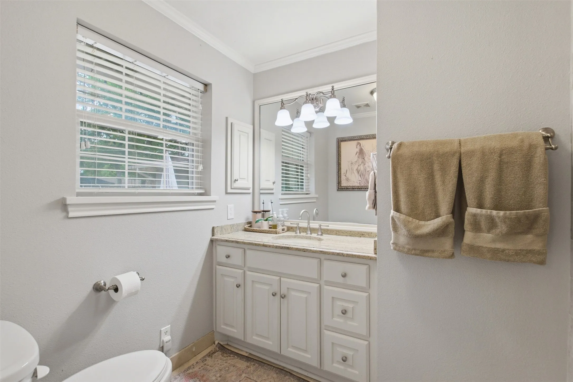 Single vanity with a light-toned countertop, white cabinetry, and a framed mirror