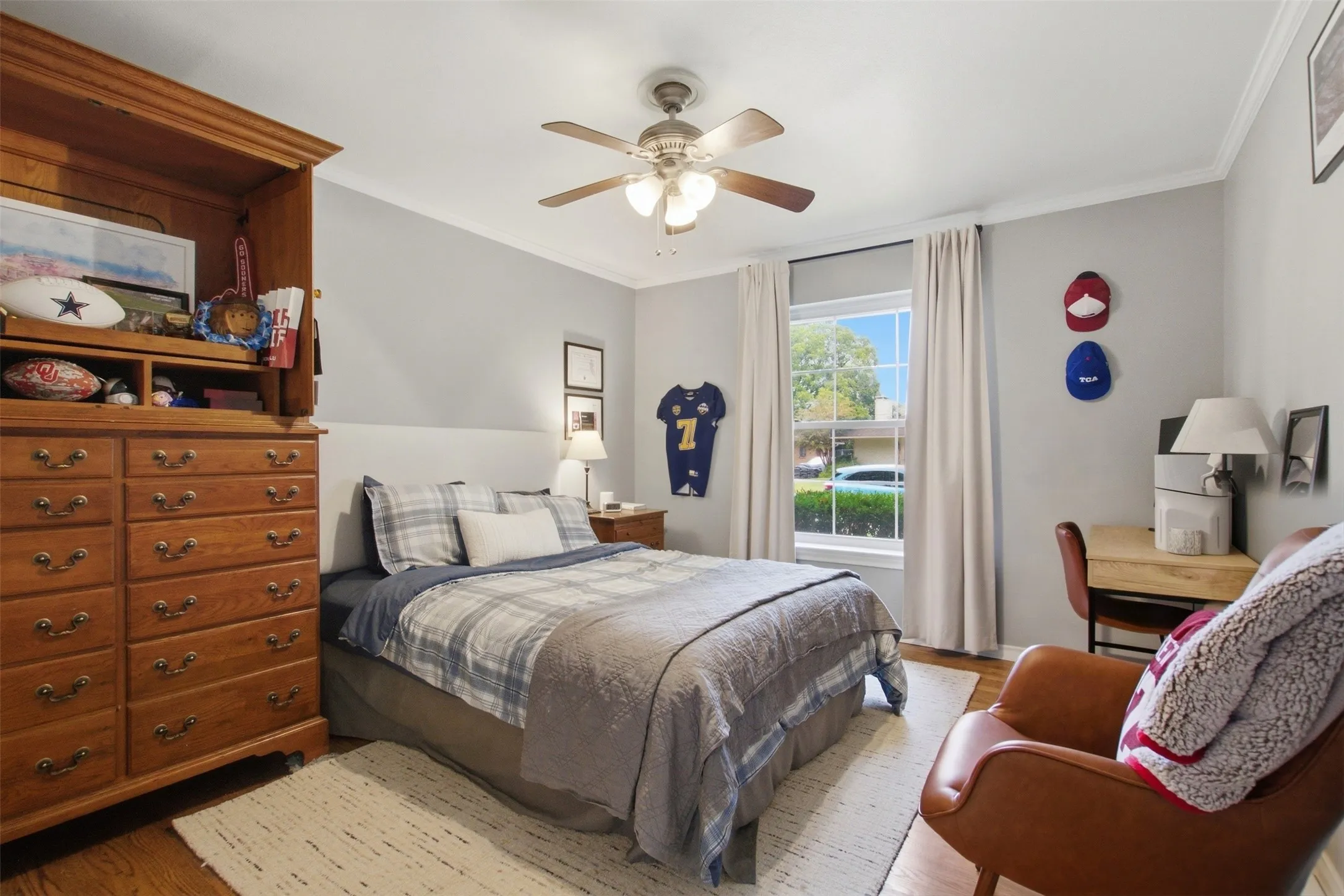 Recessed window with white trim, wood-finish flooring, ceiling fan with light fixture, and crown molding