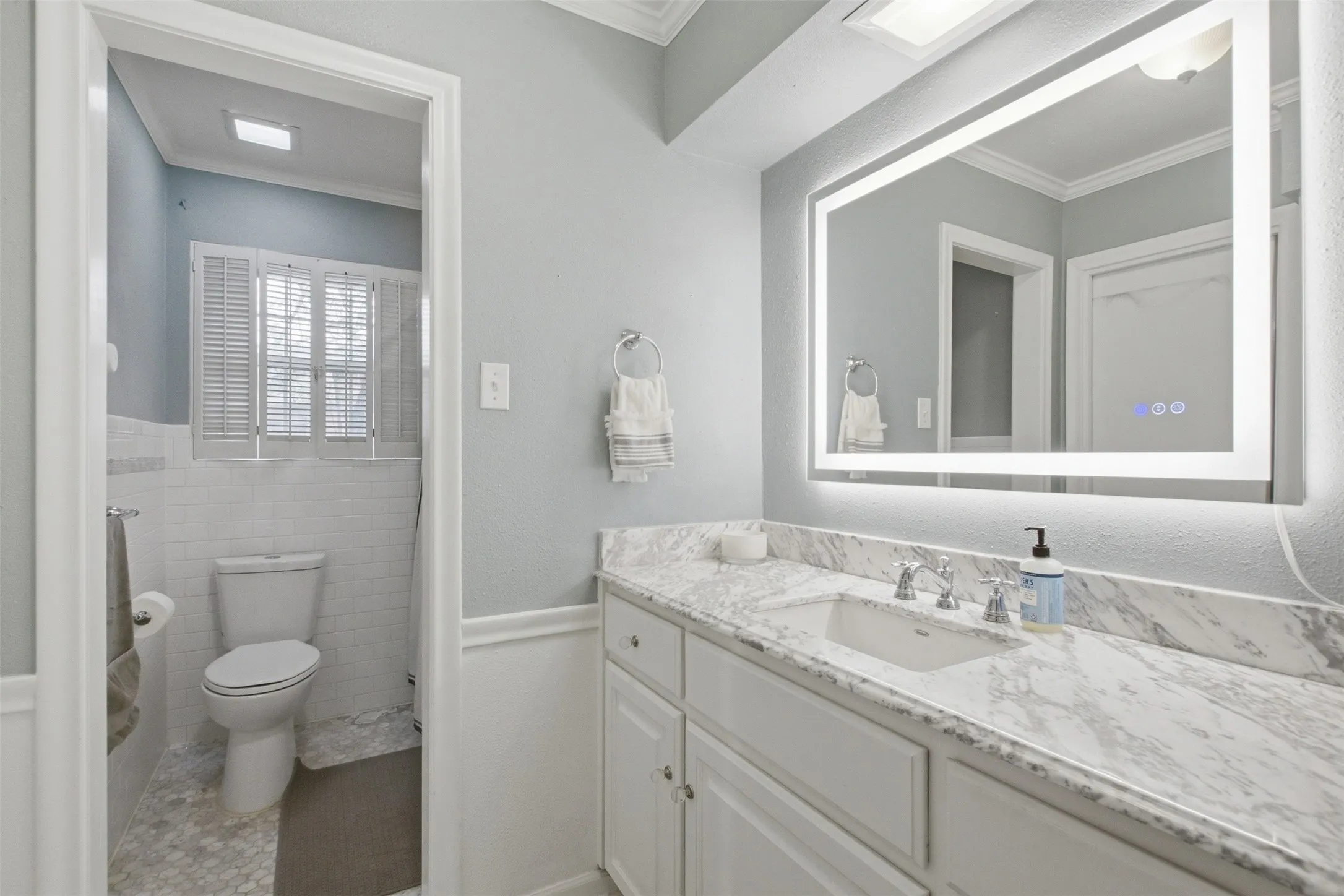 White vanity with integrated sink, stone-finish countertop, and chrome faucet