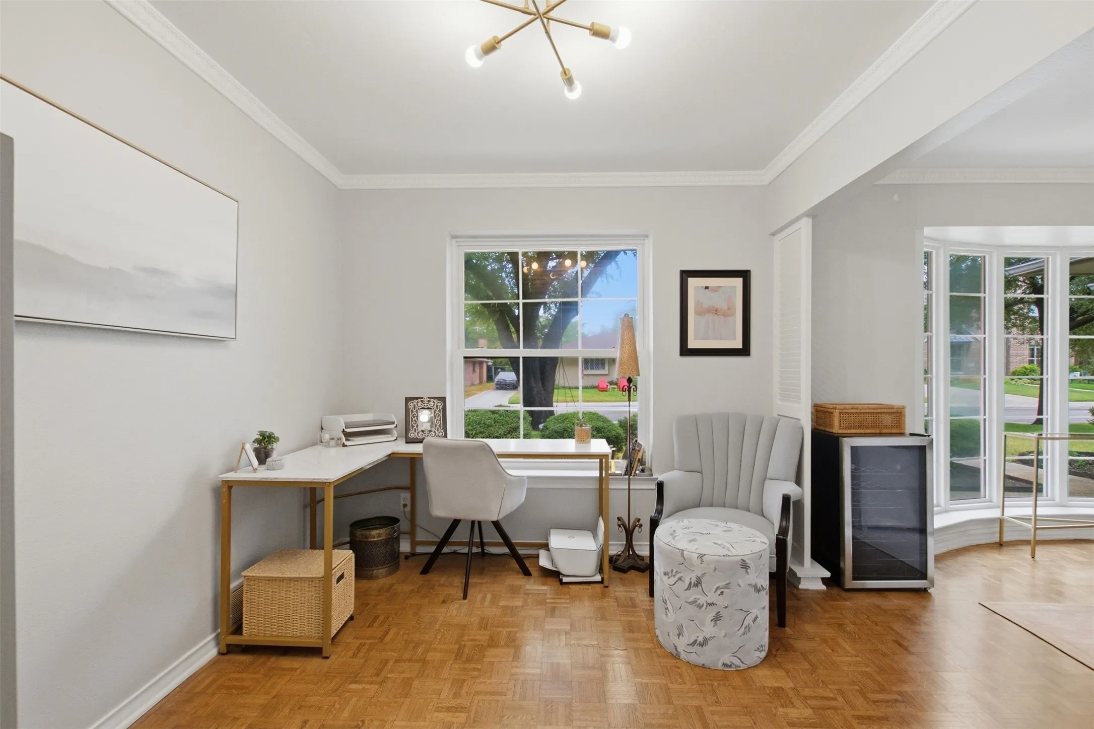 Parquet wood-finish flooring, crown molding, modern ceiling fixture, and a bay window