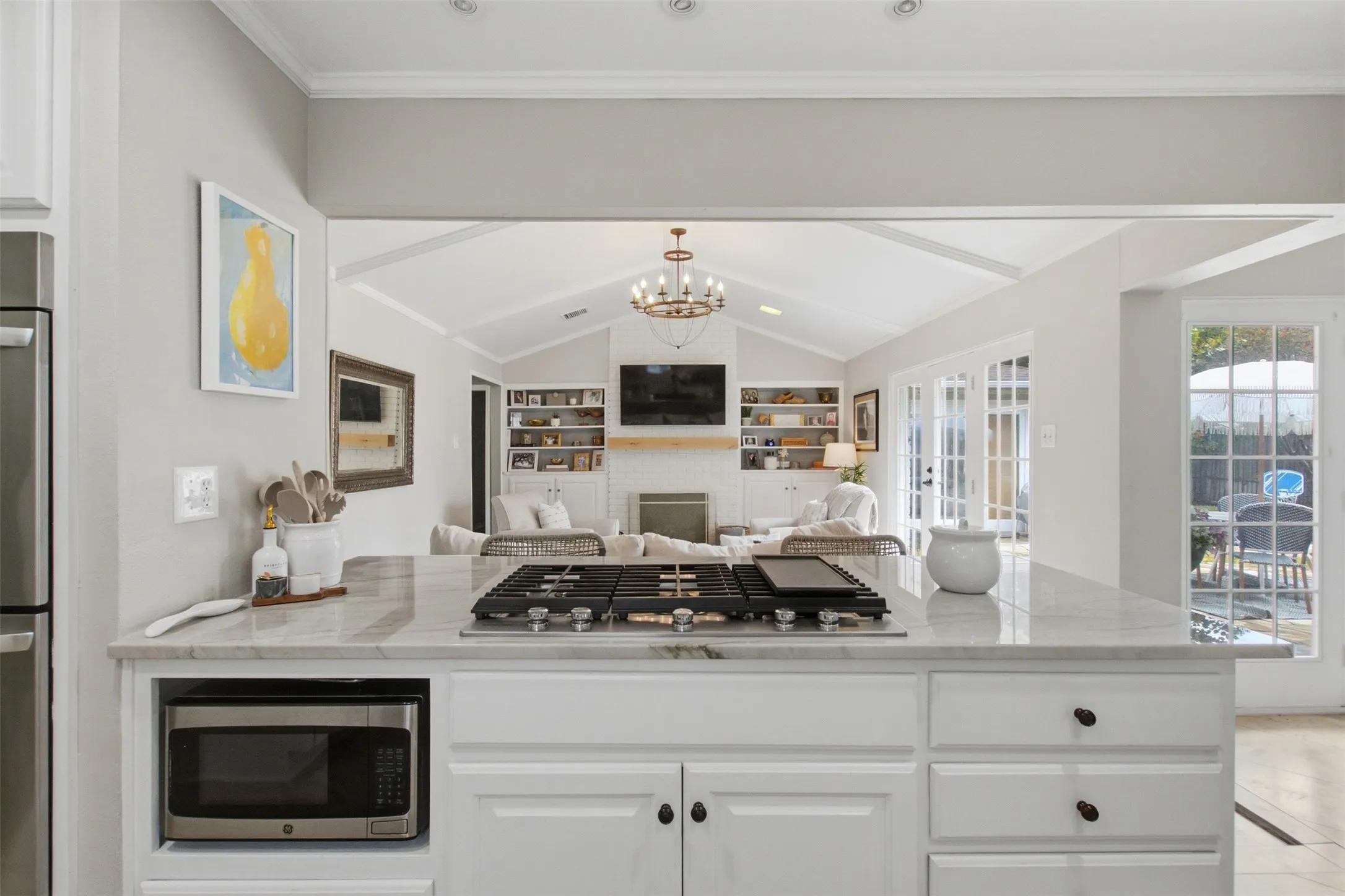 Kitchen island with a built-in cooktop, microwave, and white cabinetry