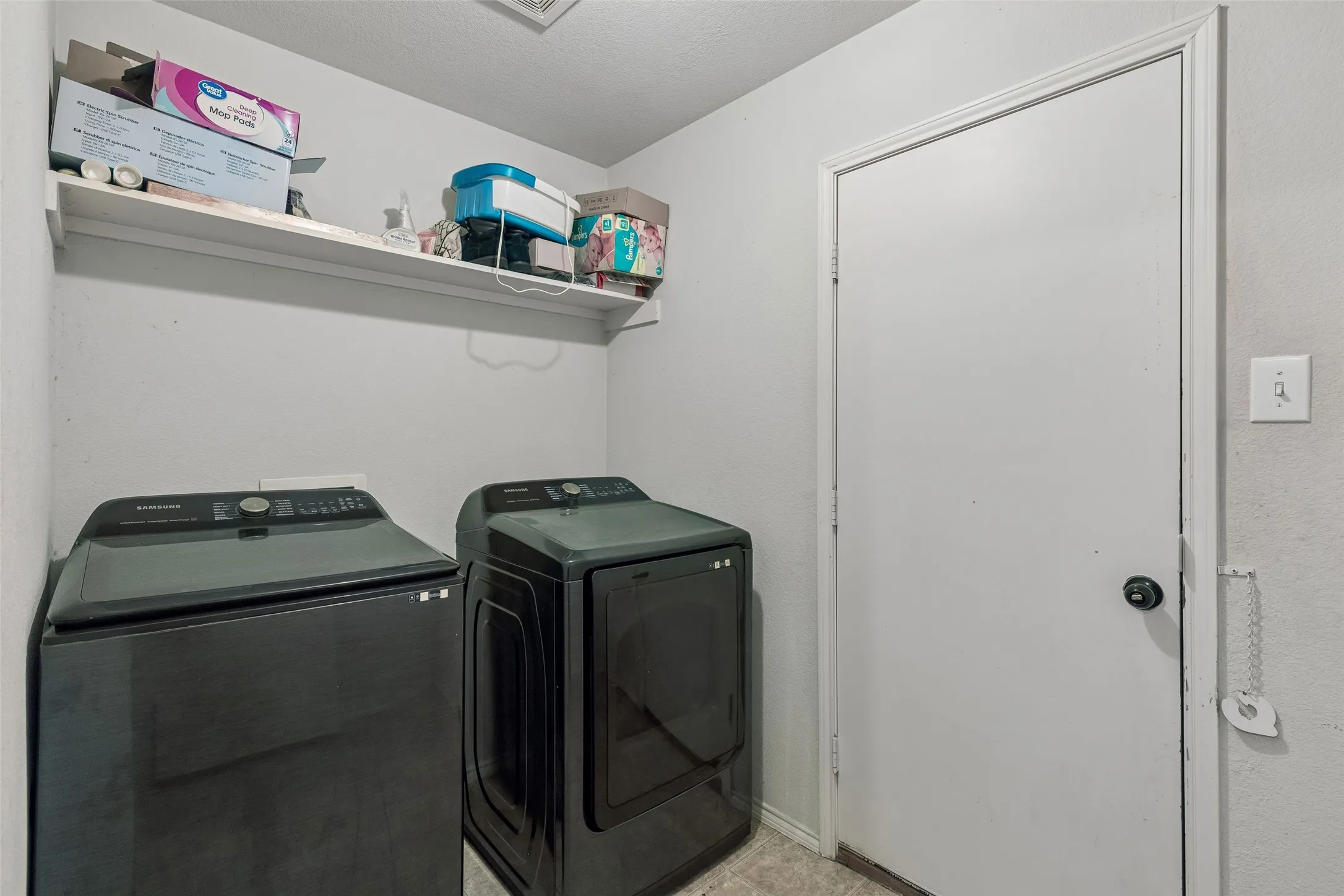 Laundry area featuring a wall-mounted shelf and overhead lighting