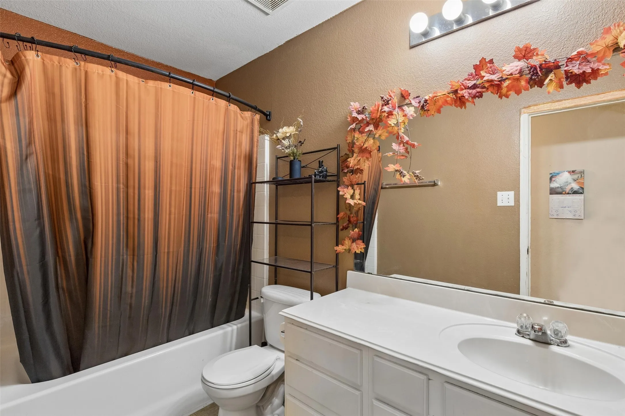 Built-in bathtub, white vanity with integrated sink, wall-mounted light fixture, and a large mirror