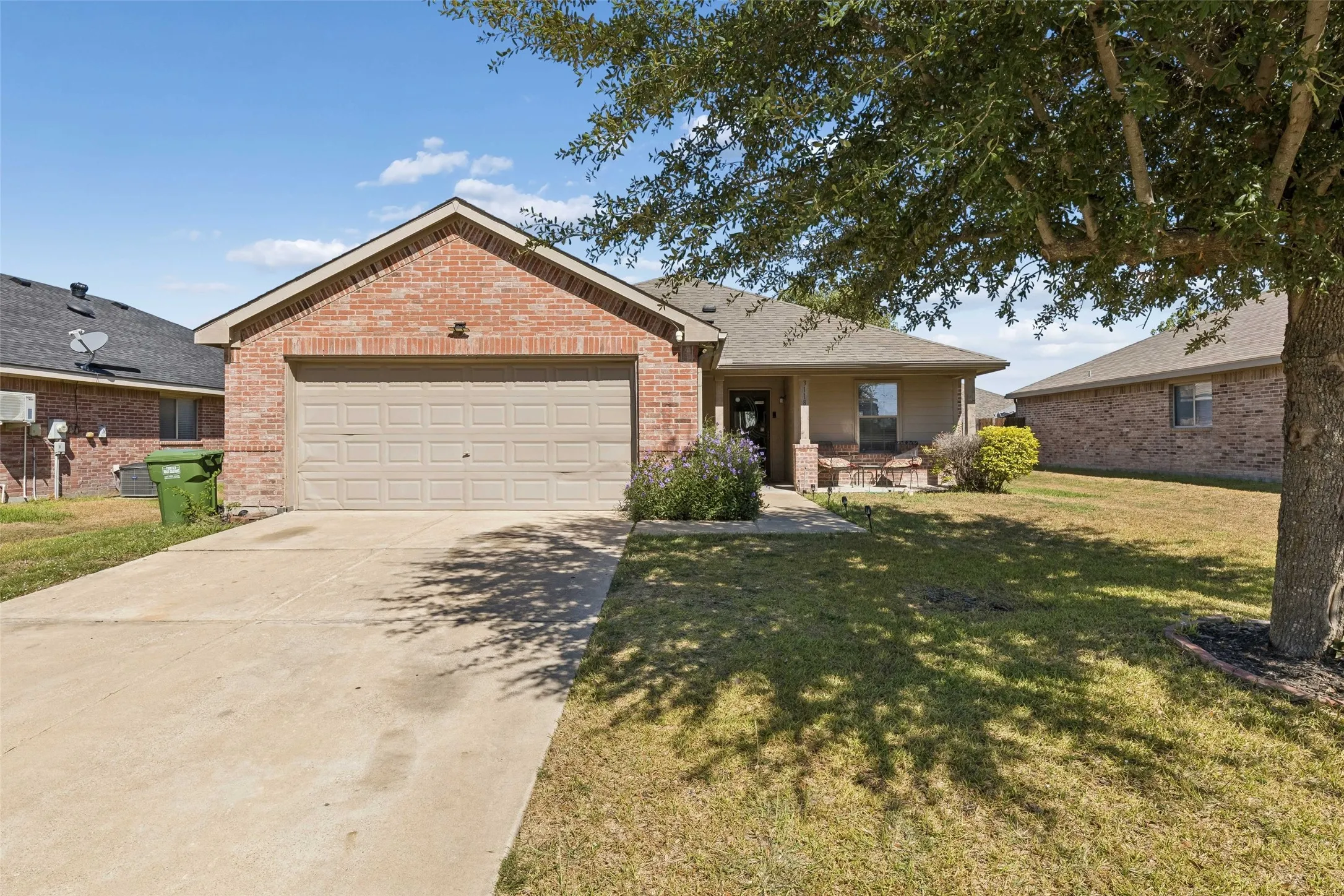 Brick exterior with a gabled roofline, two-car garage, concrete driveway, and covered front porch