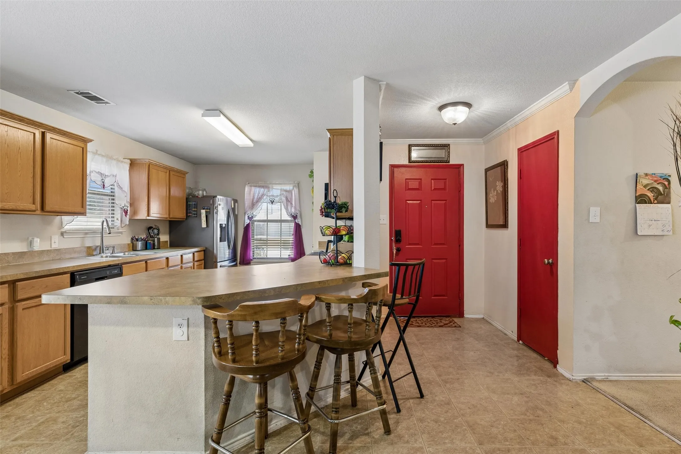 Kitchen featuring wood cabinetry, laminate countertops, a double basin sink, and a black dishwasher