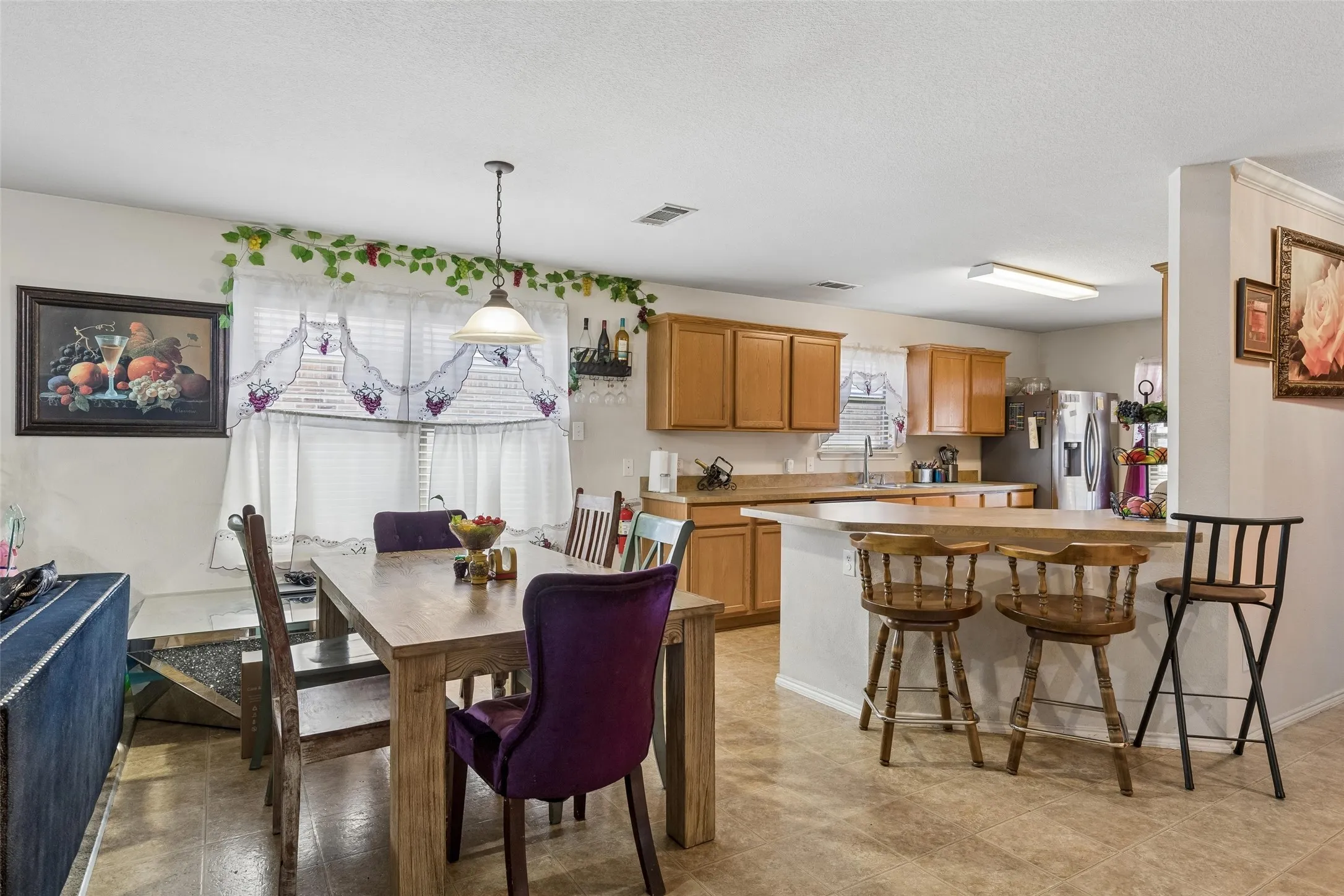 Open-concept kitchen and dining area featuring a breakfast bar, recessed lighting, and wood-finish cabinetry