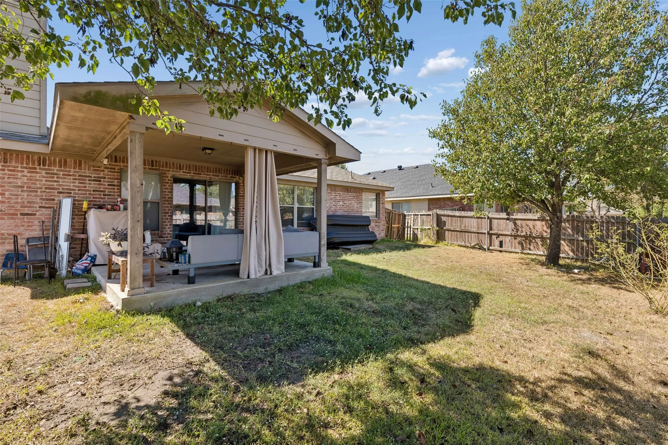 Covered patio with a concrete slab, wood support posts, and brick exterior