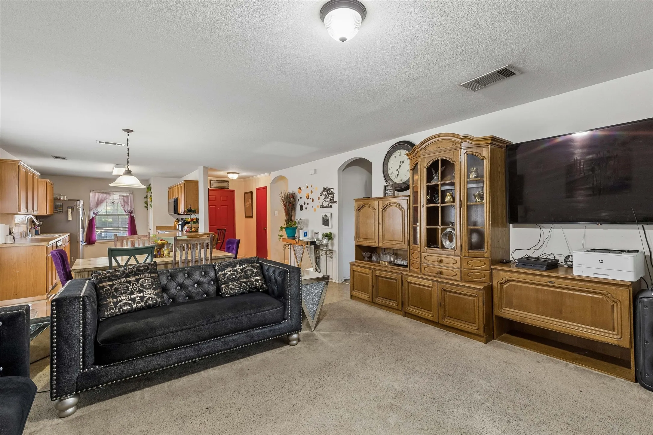 Open-concept living area with consistent flooring, recessed ceiling lighting, and archway entry