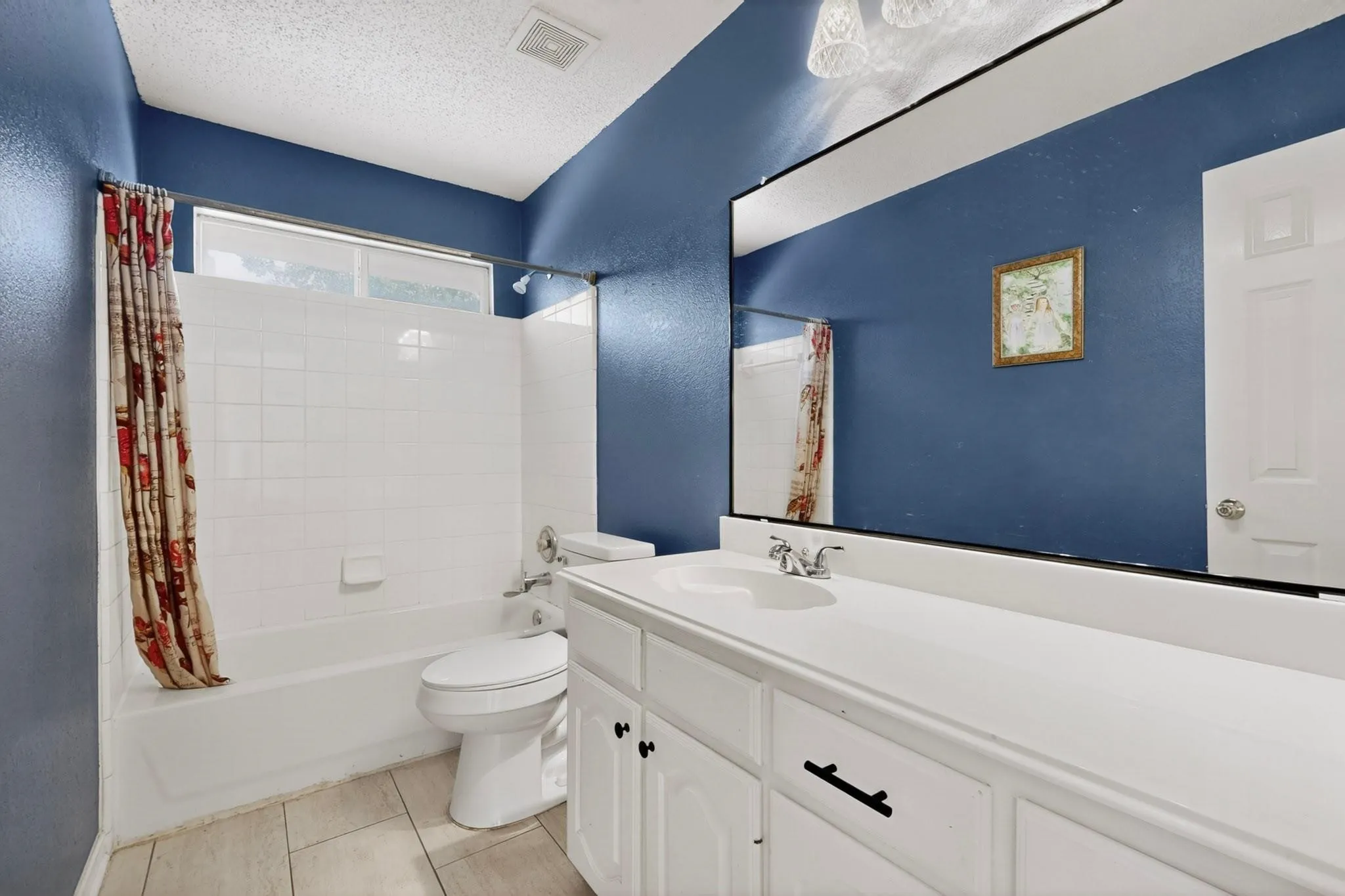 Bathroom featuring a full vanity with integrated sink, white cabinetry, and a large wall-mounted mirror