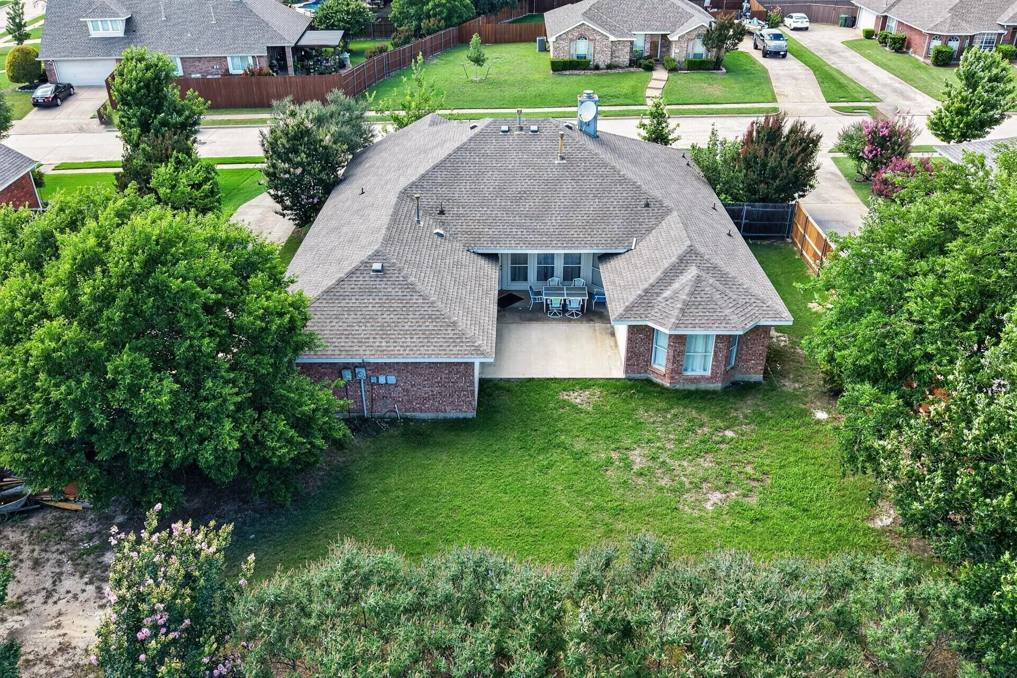 Expansive backyard with a manicured lawn, mature trees, and a brick exterior