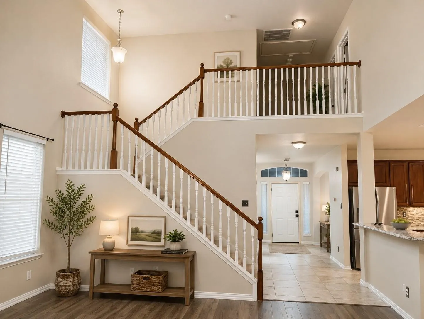 Grand entryway featuring a two-story foyer, wood-finish flooring, and a staircase with wood newel posts and handrails