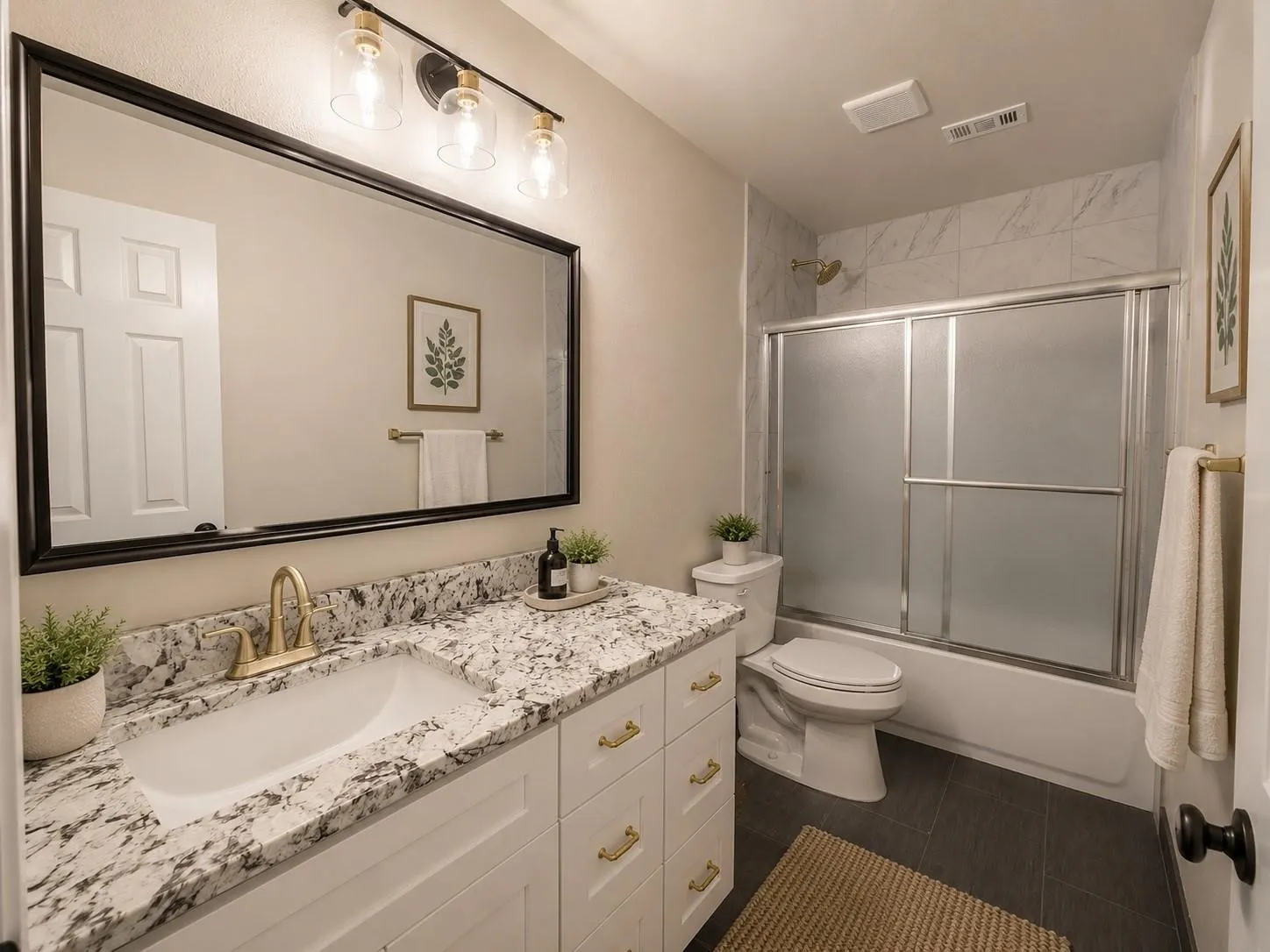 White vanity with gold hardware, a white undermount sink, and a speckled countertop