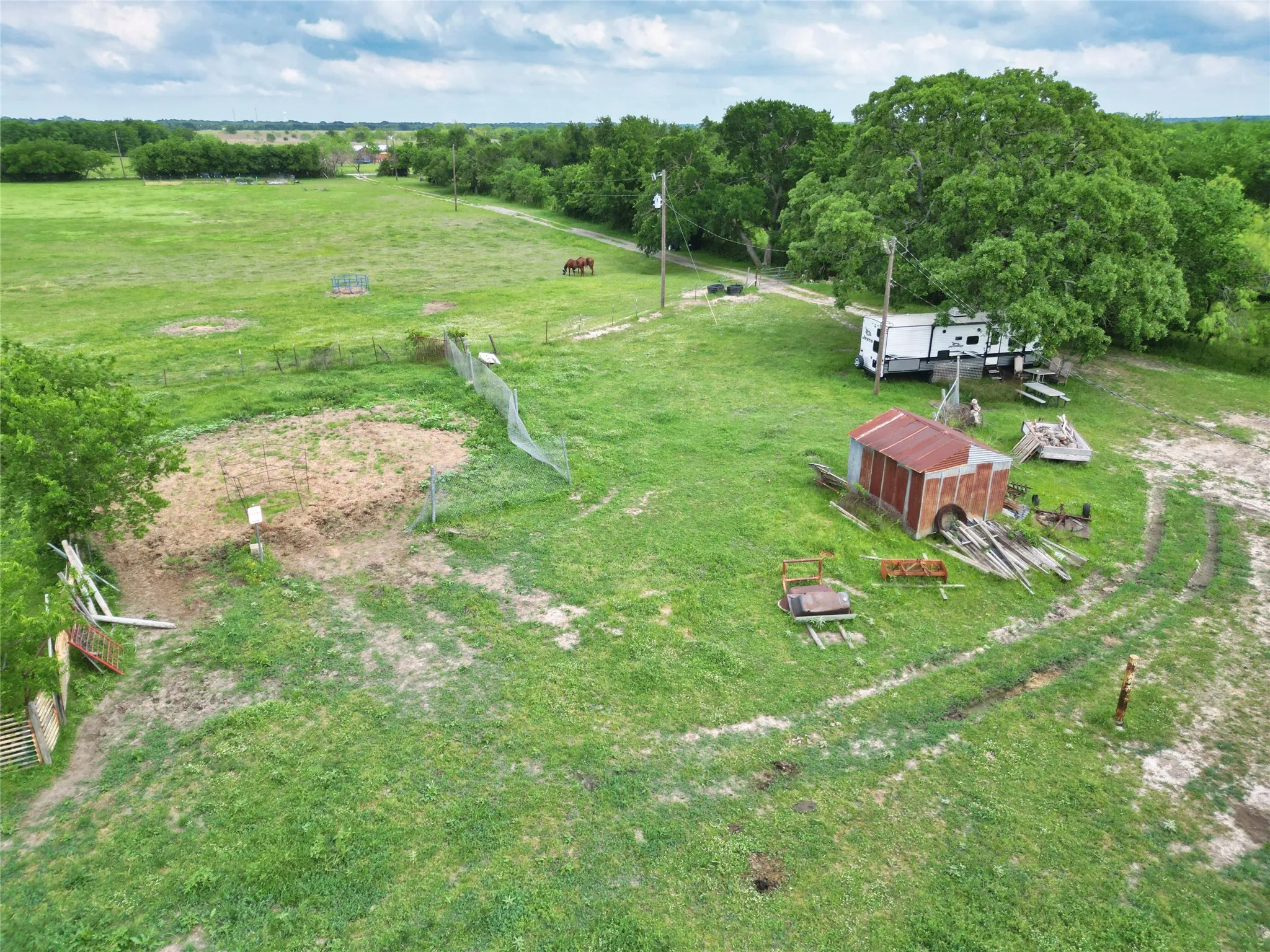 Expansive green space with perimeter fencing, mature trees, and a utility shed