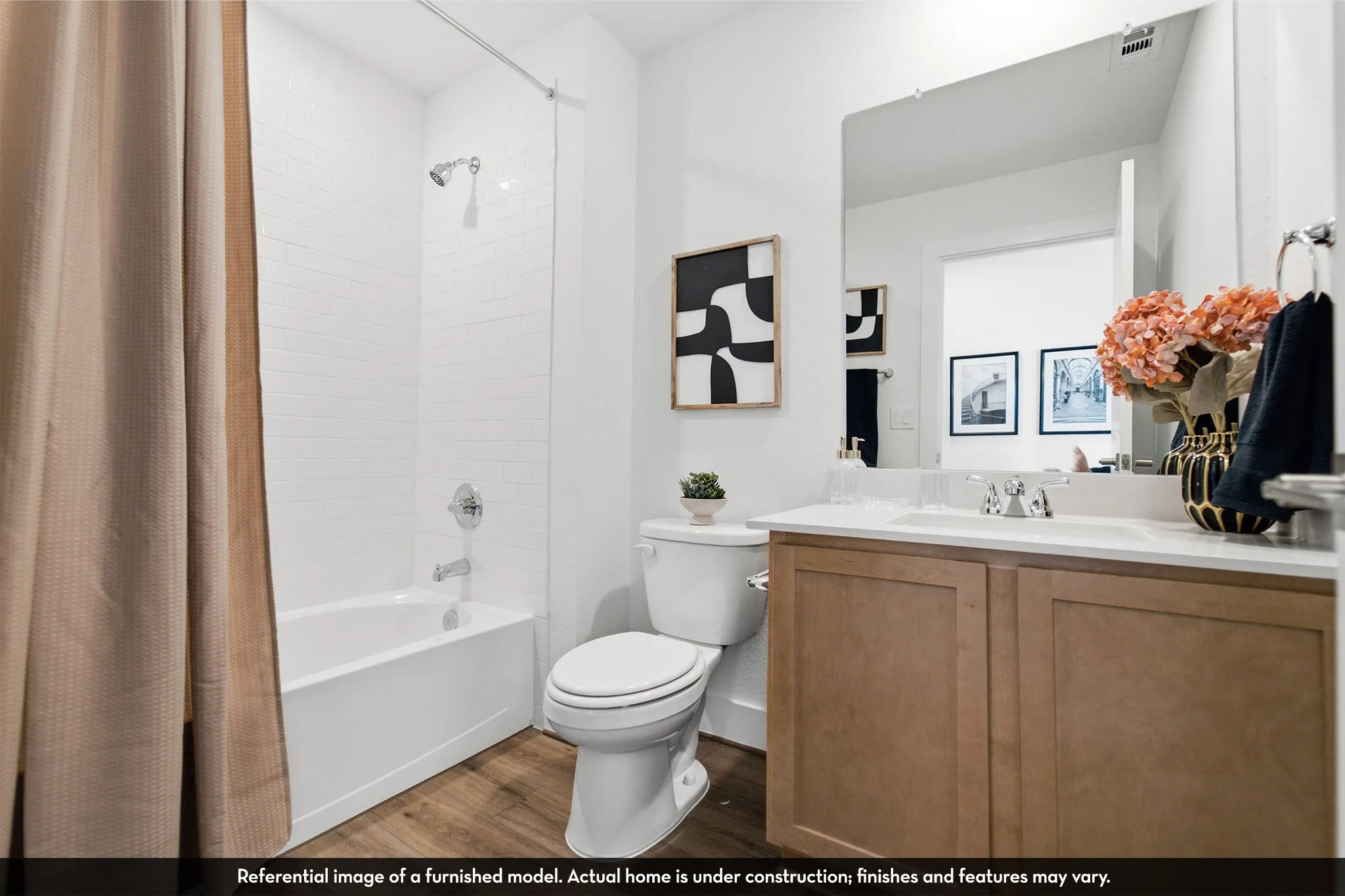 White subway tile shower surround with chrome fixtures, wood-finish flooring, and a vanity with a light-toned countertop and wood-finish cabinetry