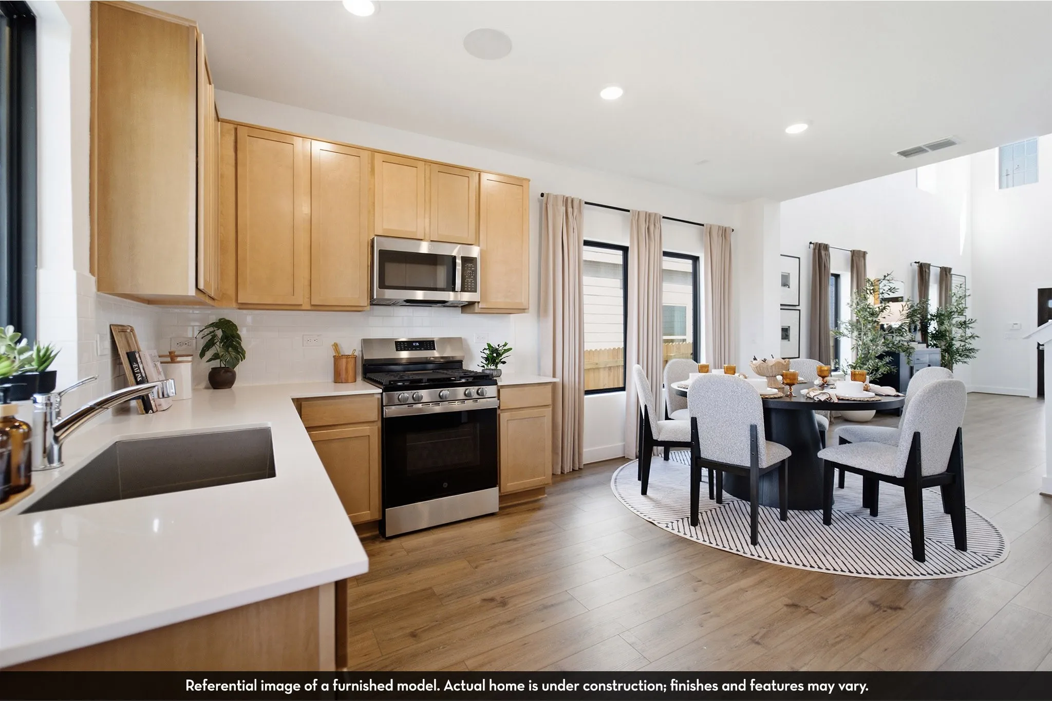 Kitchen with light wood-finish cabinetry, white countertops, stainless steel appliances, and a white subway tile backsplash