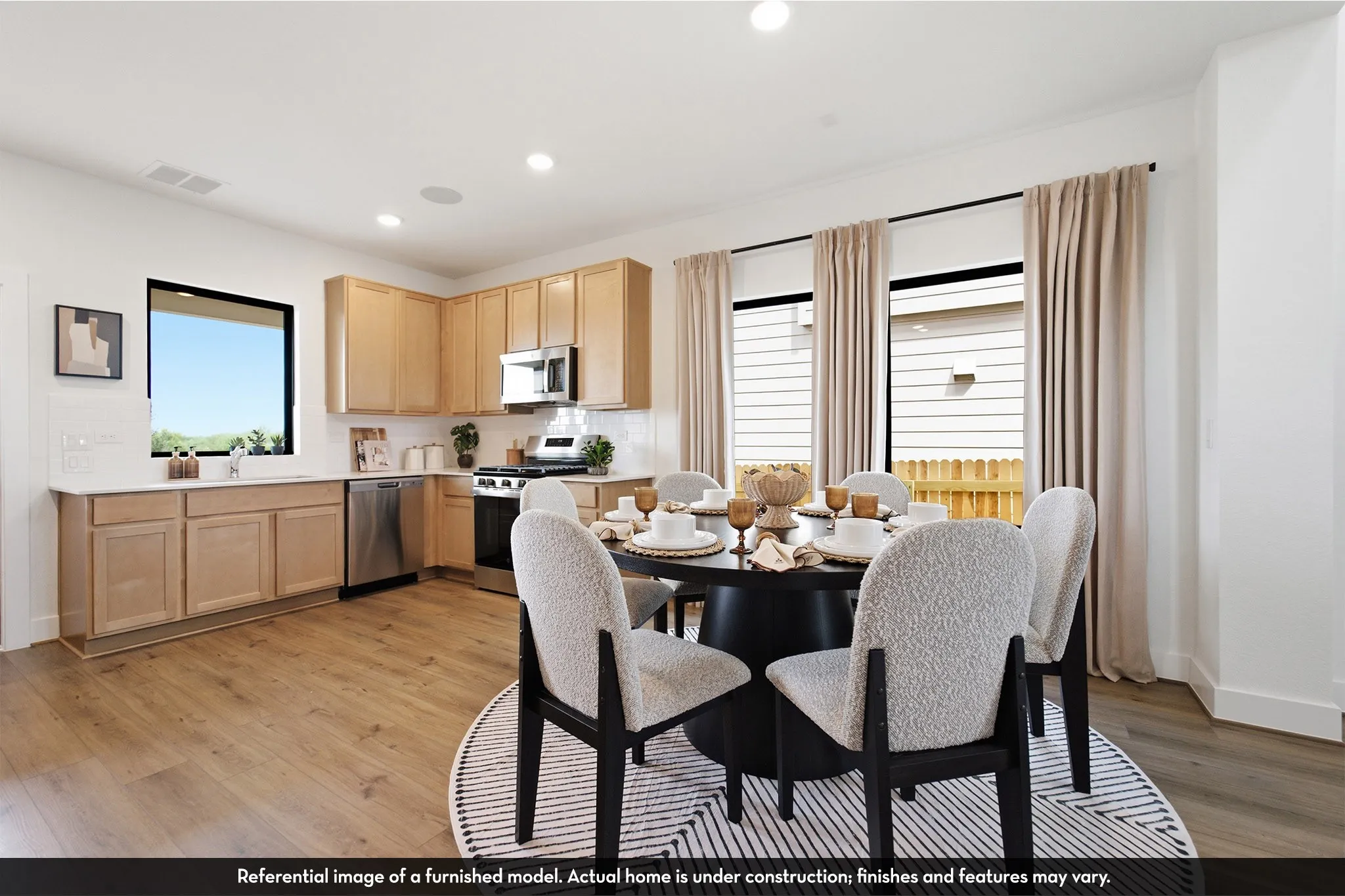 Open-concept kitchen and dining area featuring wood-finish flooring, recessed lighting, and multiple windows