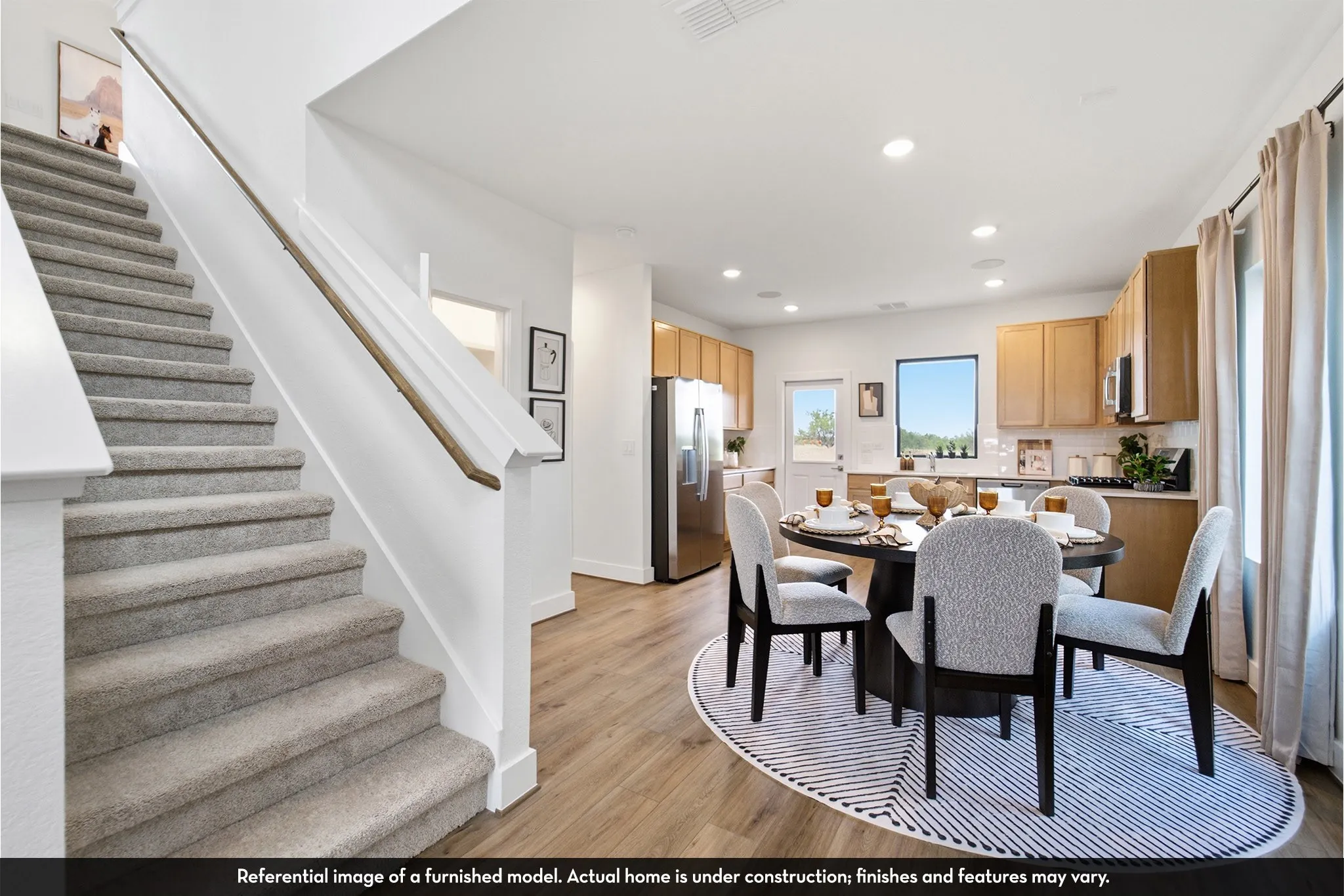 Open-concept living space with wood-finish flooring, recessed lighting, and a carpeted staircase with a wood handrail